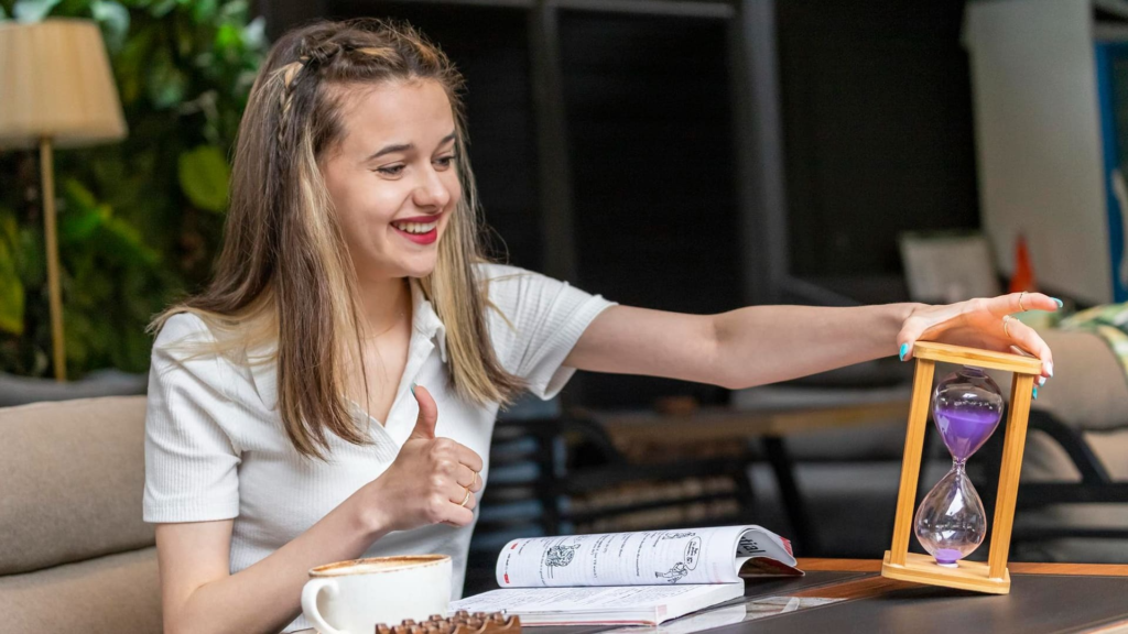A women holding Sandglass while reading books and posing

